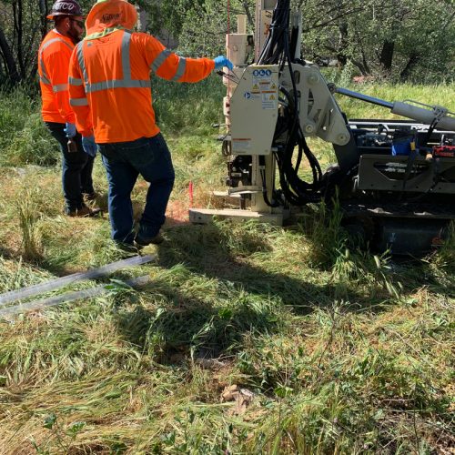 Workers standing next to a large drill rig